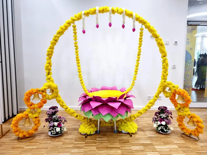 Traditional lotus swing décor with yellow and orange floral garlands, hanging bells and flower arrangements