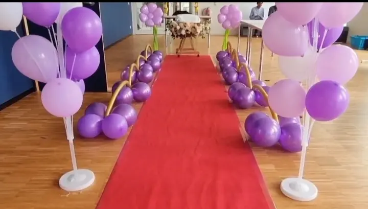 Purple and lavender balloon welcome aisle décor with a red carpet and gold accents